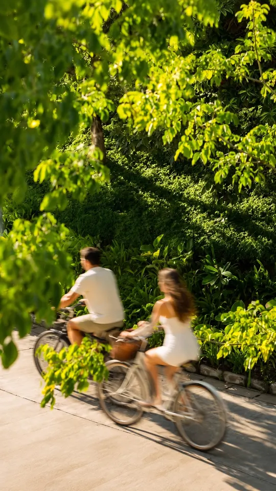 Couple cycling along a path through dense greenery, Abu Dhabi Mira Hills